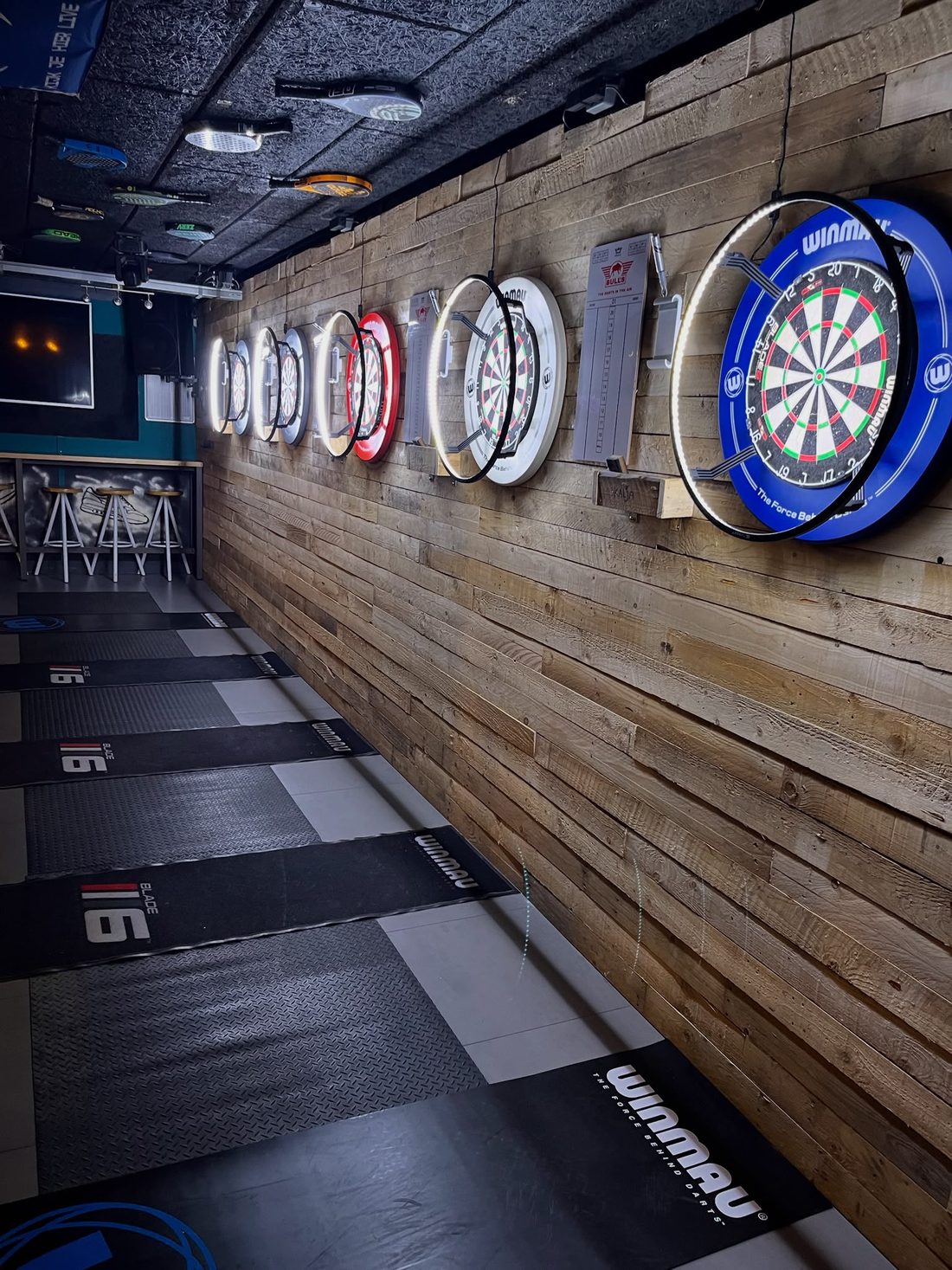 De darthoek van Logan's Pub met een rij verlichte dartborden
